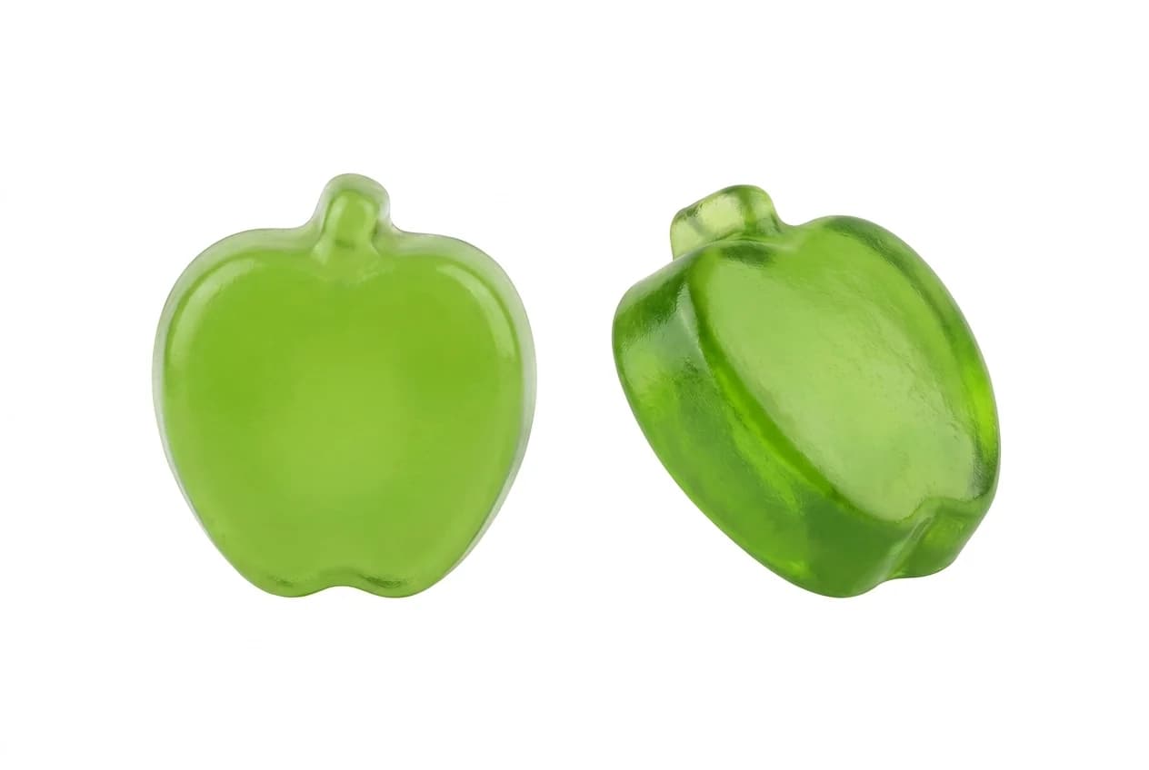 Two green apple-shaped gummies on white, one upright and one angled to show the moulded profile