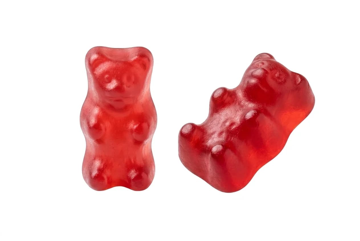 Two red bear-shaped gummies on white, one upright and one angled to show the moulded profile
