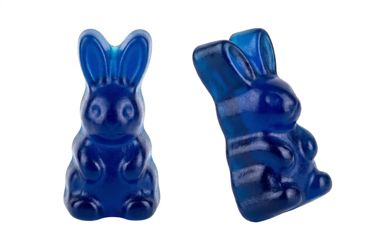 Two deep blue bunny-shaped gummies on white, one upright and one angled to show the moulded profile
